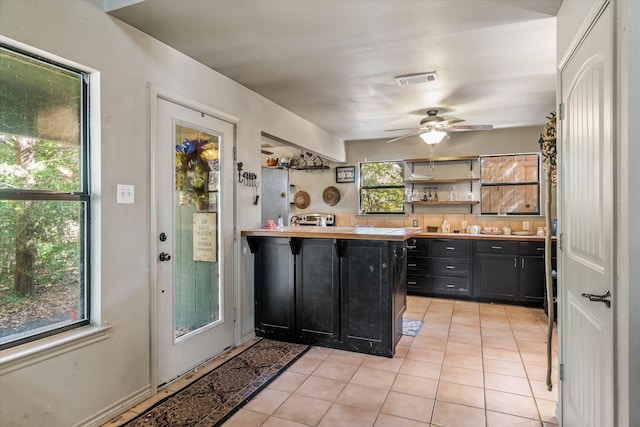 kitchen featuring kitchen peninsula, a wealth of natural light, light tile patterned flooring, and ceiling fan