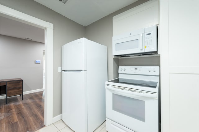 kitchen with white appliances, hardwood / wood-style floors, and white cabinets