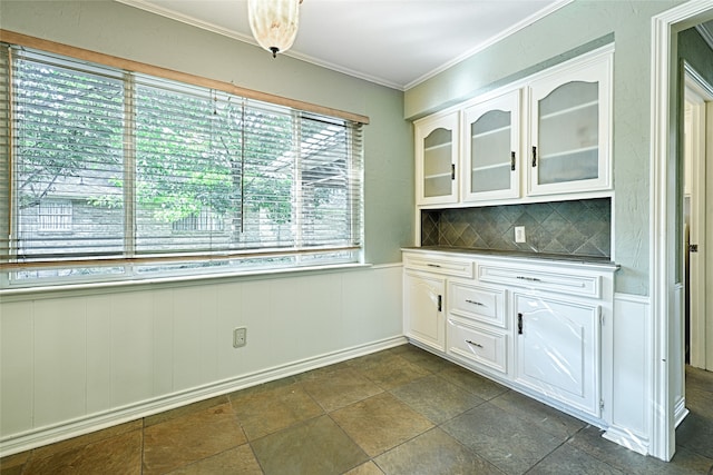 kitchen featuring crown molding, white cabinetry, and backsplash