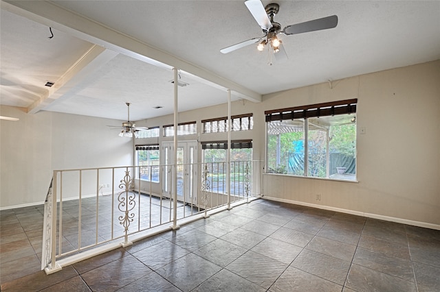 empty room featuring a wealth of natural light, beam ceiling, a textured ceiling, and ceiling fan