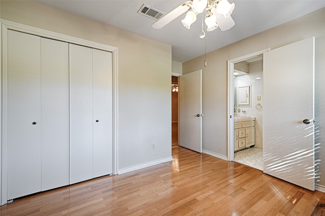 unfurnished bedroom with light hardwood / wood-style flooring, a closet, ensuite bath, and ceiling fan