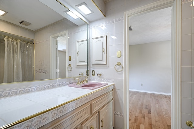 bathroom with tile walls, vanity, wood-type flooring, and walk in shower