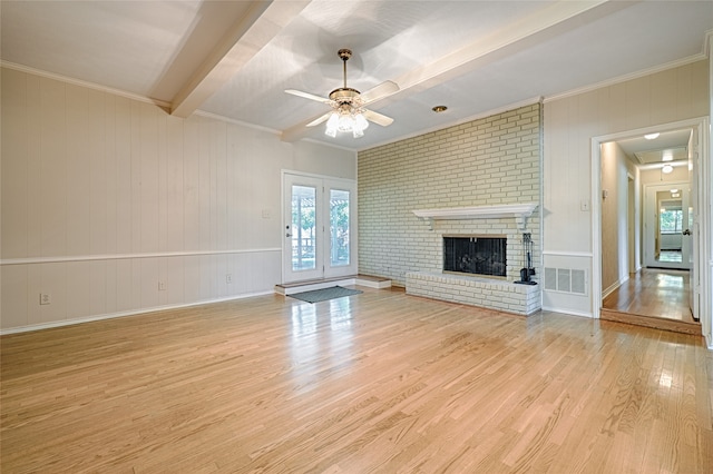 unfurnished living room featuring ceiling fan, light wood-type flooring, a brick fireplace, ornamental molding, and beamed ceiling