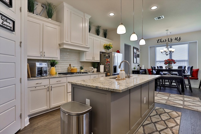 kitchen with pendant lighting, an island with sink, white cabinets, a notable chandelier, and dark hardwood / wood-style flooring