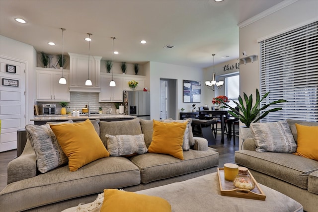 living room with a notable chandelier, hardwood / wood-style floors, and crown molding