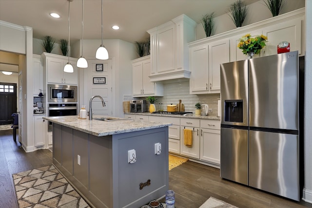 kitchen with an island with sink, sink, stainless steel appliances, and white cabinets