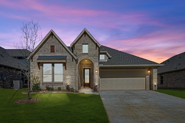 view of front of house featuring a garage, a yard, and central AC unit