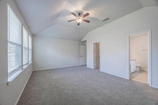 unfurnished bedroom featuring connected bathroom, light carpet, baseboards, visible vents, and lofted ceiling
