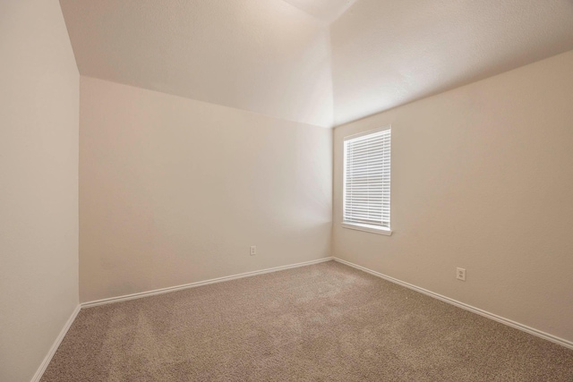 carpeted empty room with baseboards and vaulted ceiling