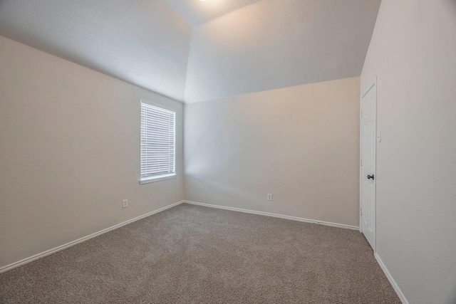 empty room featuring carpet flooring, baseboards, and lofted ceiling