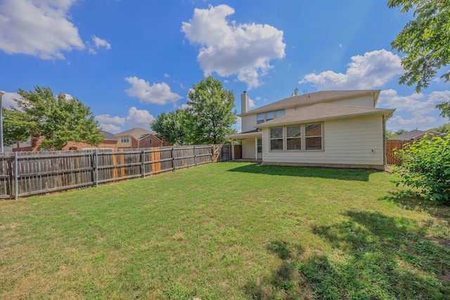 rear view of property with a lawn, a fenced backyard, and a chimney