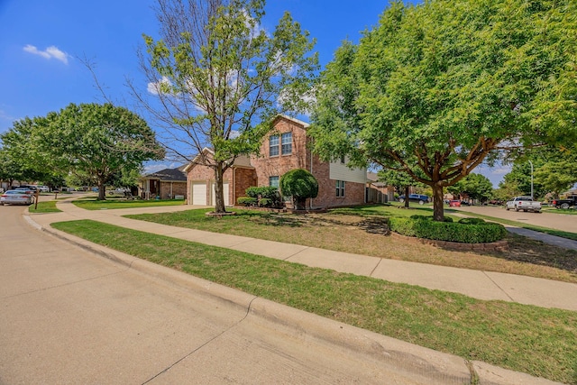 traditional-style house with a garage, brick siding, a front lawn, and driveway