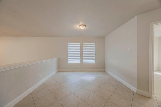 spare room with baseboards and light tile patterned floors