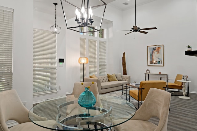 living room with wood-type flooring, ornamental molding, ceiling fan, and a high ceiling