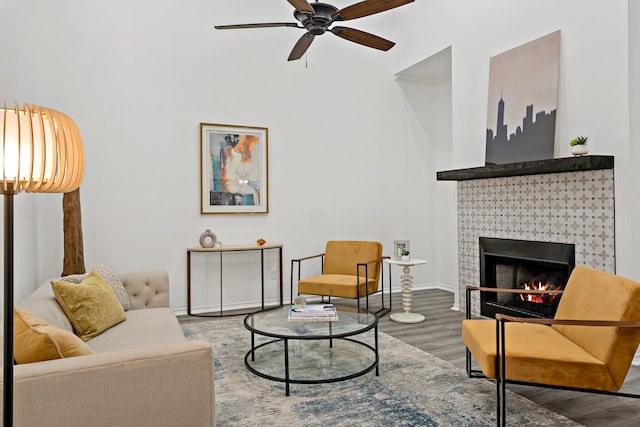 living room featuring wood-type flooring, a tile fireplace, and ceiling fan