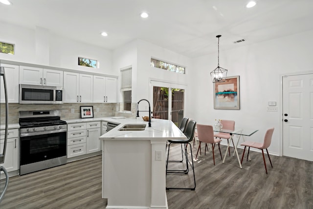 kitchen with sink, a breakfast bar, appliances with stainless steel finishes, white cabinets, and decorative light fixtures