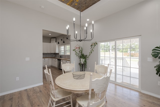 dining space with sink, light wood-type flooring, and a high ceiling