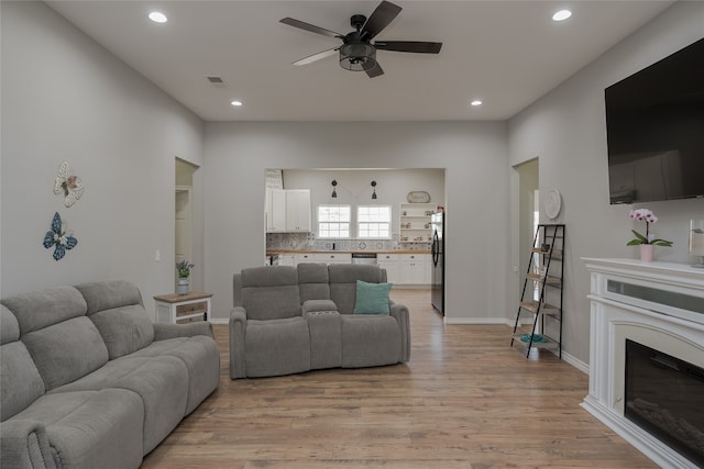 living room featuring ceiling fan and light hardwood / wood-style floors