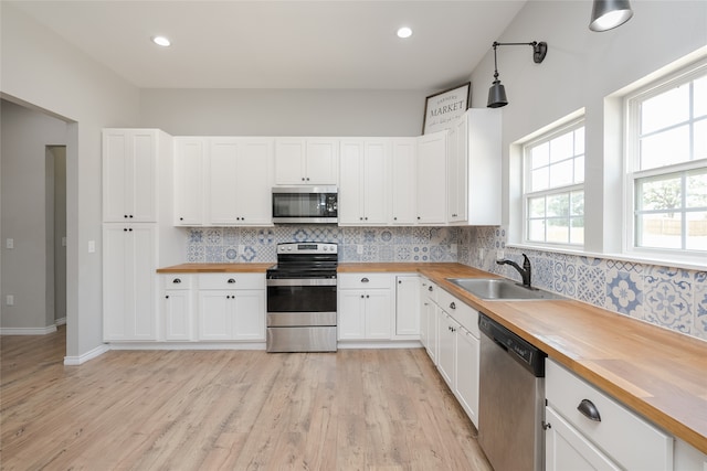 kitchen featuring white cabinets, appliances with stainless steel finishes, sink, and wooden counters