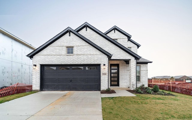 view of front of home with driveway, a garage, fence, a front yard, and brick siding