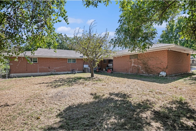 rear view of property with central AC unit and a lawn