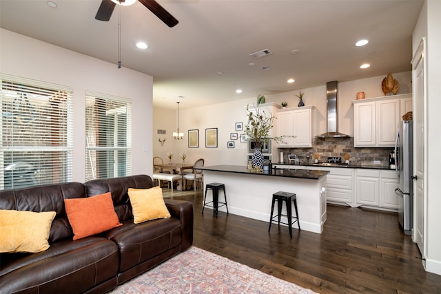 living room featuring ceiling fan with notable chandelier and dark hardwood / wood-style flooring