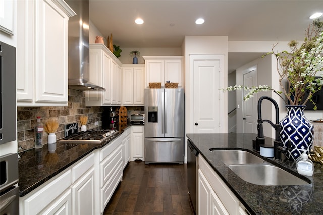 kitchen with dark wood-type flooring, sink, white cabinets, wall chimney range hood, and stainless steel appliances