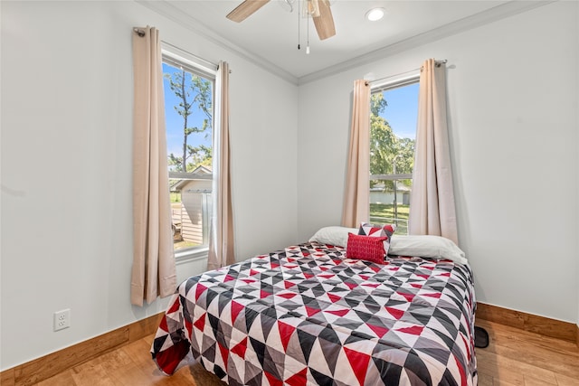 bedroom featuring ornamental molding, light hardwood / wood-style floors, ceiling fan, and multiple windows