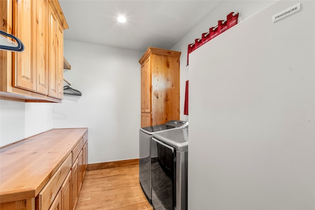 clothes washing area featuring cabinets, light hardwood / wood-style floors, and independent washer and dryer