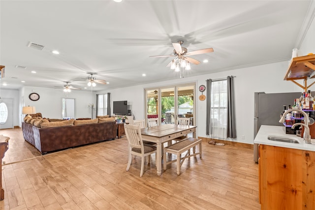 dining space with light wood-type flooring, crown molding, and sink