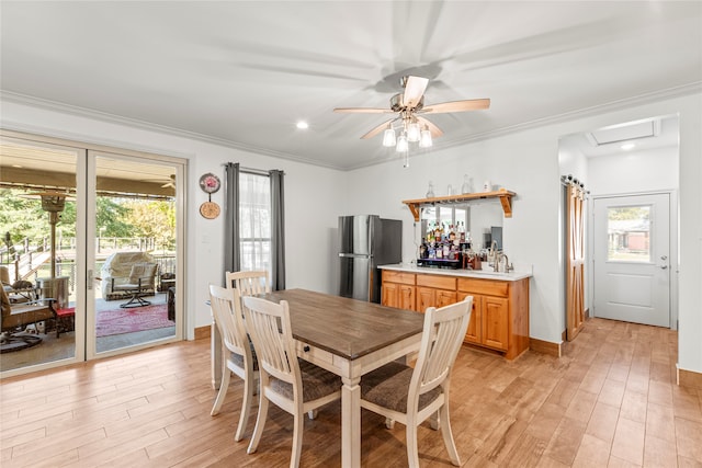 dining room with ceiling fan, light wood-type flooring, crown molding, and a healthy amount of sunlight