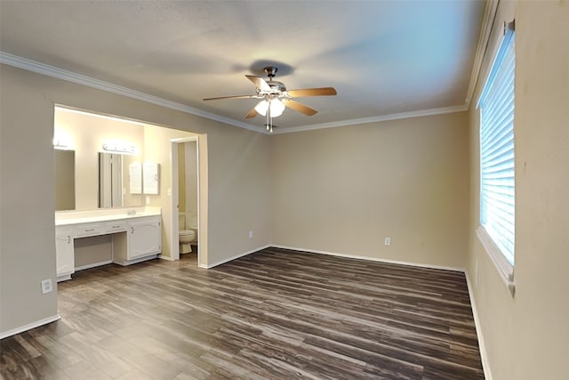 unfurnished bedroom featuring ensuite bath, ornamental molding, ceiling fan, built in desk, and dark hardwood / wood-style floors