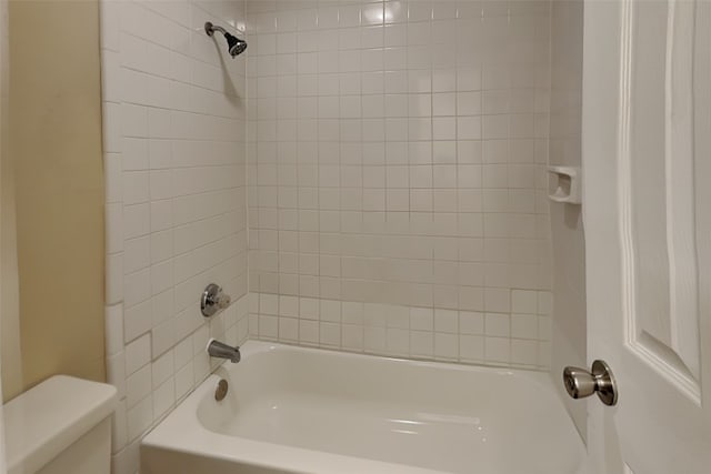 bathroom featuring toilet and tiled shower / bath