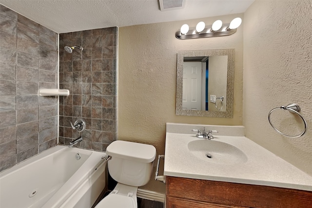 full bathroom featuring a textured ceiling, vanity, toilet, and tiled shower / bath