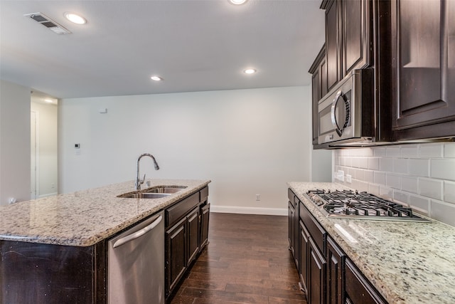 kitchen featuring sink, a center island with sink, appliances with stainless steel finishes, dark hardwood / wood-style floors, and decorative backsplash