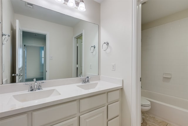 full bathroom with tiled shower / bath, tile patterned floors, vanity, and toilet