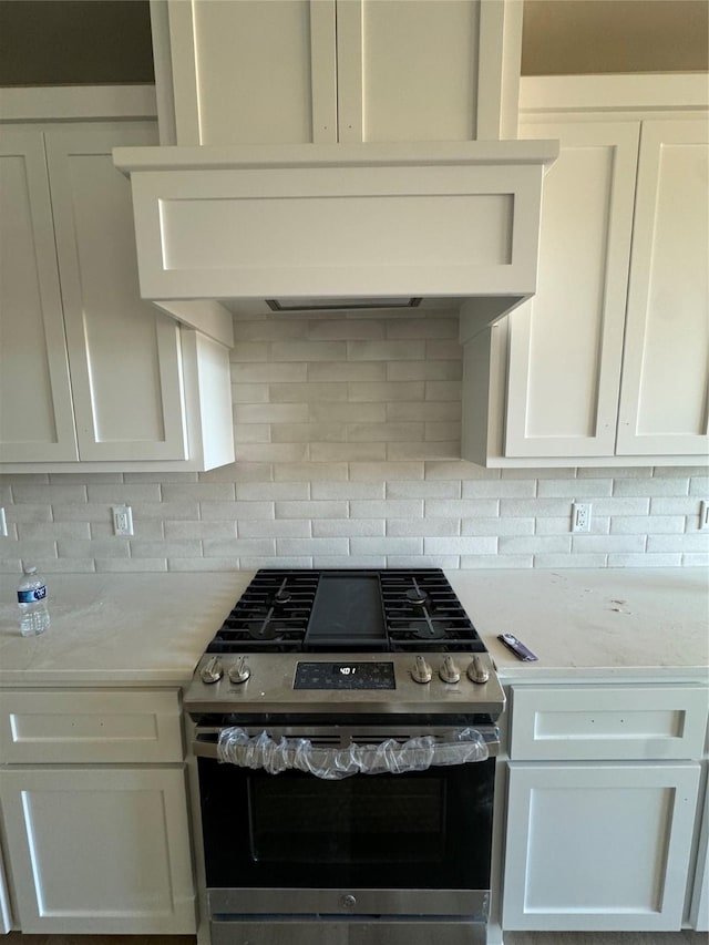 kitchen with decorative backsplash, ventilation hood, white cabinets, and stainless steel range with gas stovetop