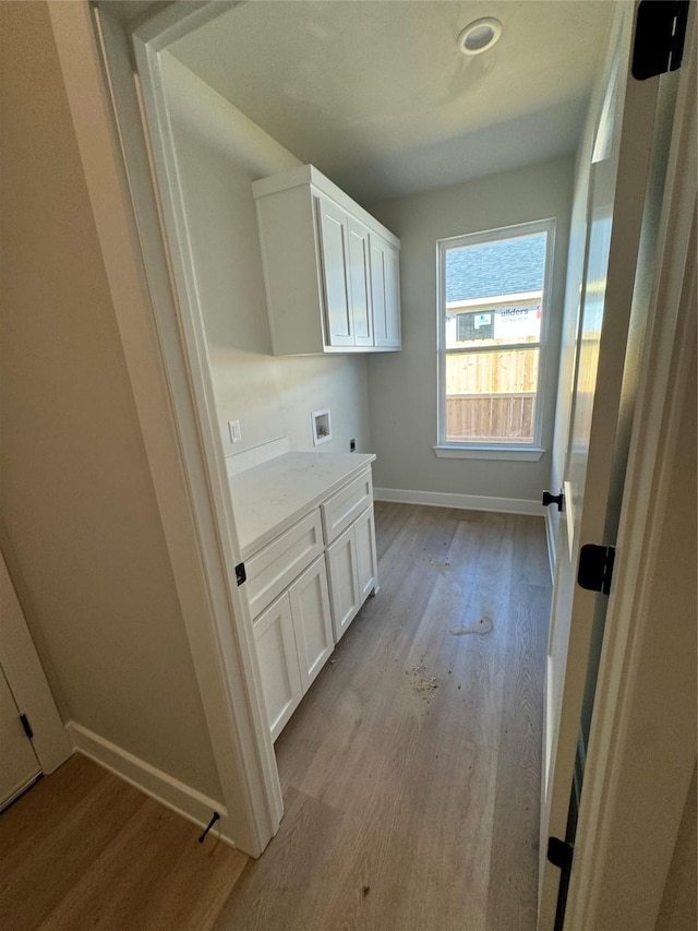 laundry room featuring cabinets, hookup for a washing machine, and light hardwood / wood-style floors