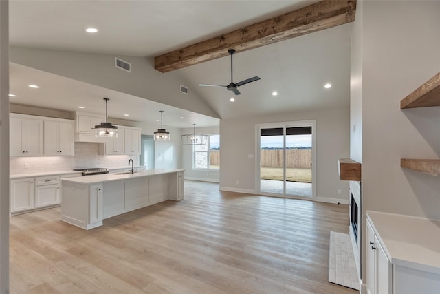 kitchen with white cabinets, hanging light fixtures, ceiling fan, an island with sink, and light hardwood / wood-style floors