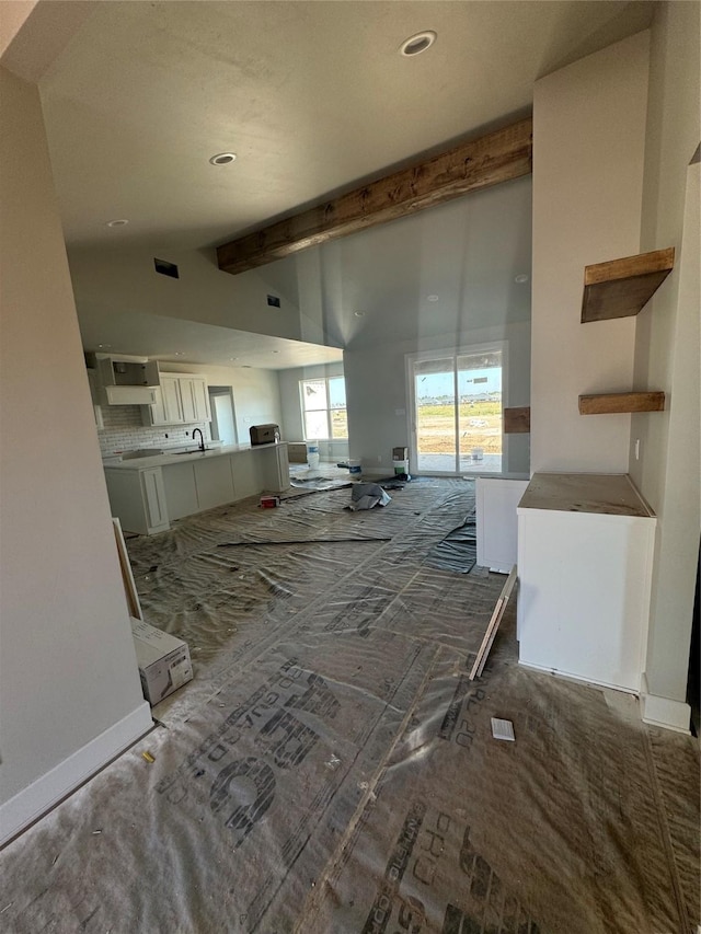 hallway featuring vaulted ceiling with beams, dark carpet, and sink