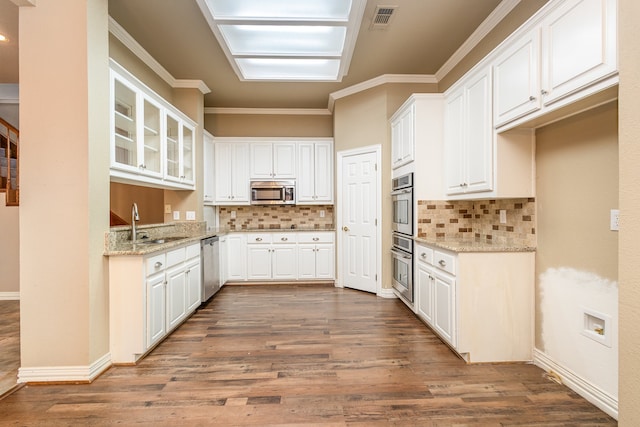 kitchen with decorative backsplash, light stone countertops, white cabinets, and stainless steel appliances