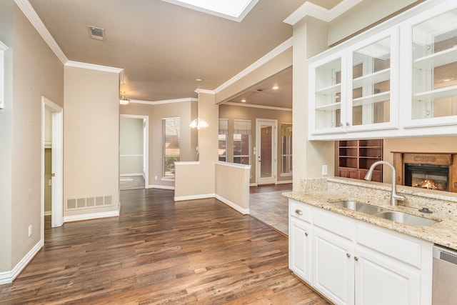 kitchen with stainless steel dishwasher, sink, ornamental molding, white cabinets, and light stone counters