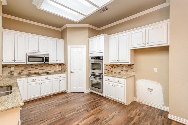 kitchen with light stone countertops, white cabinetry, backsplash, and stainless steel appliances