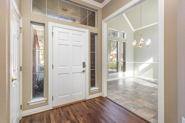 foyer with vaulted ceiling, dark wood-type flooring, crown molding, and a notable chandelier