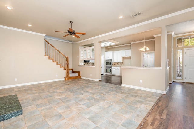 unfurnished living room with ornamental molding and ceiling fan with notable chandelier