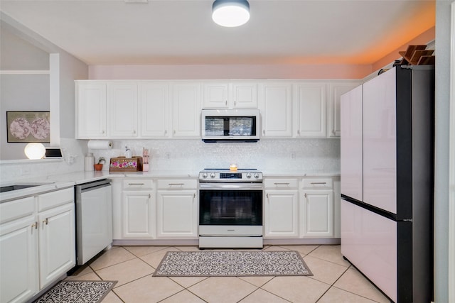 kitchen with white appliances, white cabinetry, light tile patterned floors, and tasteful backsplash