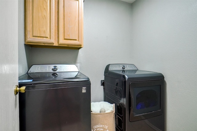 washroom featuring cabinets and washer and clothes dryer