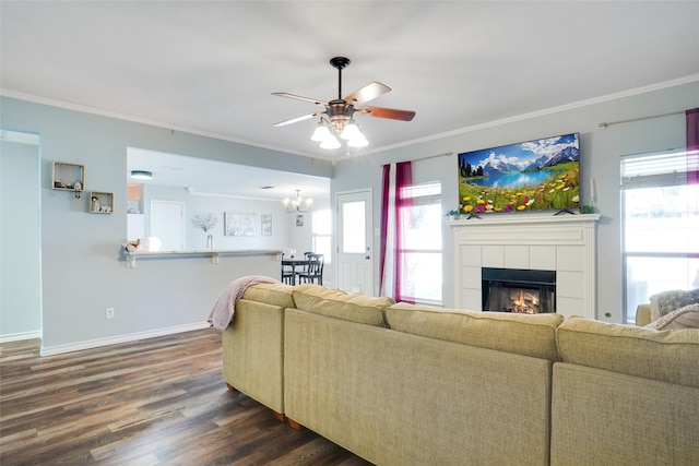 living room with ornamental molding, ceiling fan with notable chandelier, a fireplace, and dark hardwood / wood-style flooring