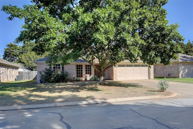 view of front facade with a front yard, central air condition unit, and a garage