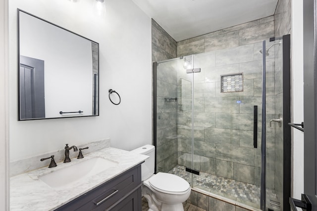 bathroom featuring a shower with door, vanity, and toilet